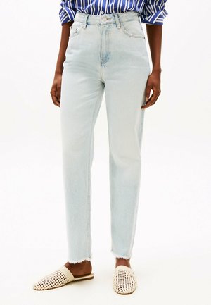 Lichtblauwe high-waisted jeans met een rechte pijp, voorzien van een onafgewerkte zoom en subtiele vervaging, gecombineerd met beige geweven instap schoenen.