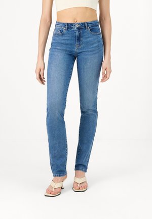 Lichtblauwe hoge taille jeans met een rechte pasvorm, vijf zakken, en een subtiele vervaagde textuur, gecombineerd met beige hakken.