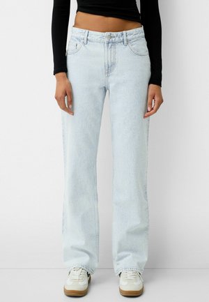 Lichtblauwe denim wijde jeans met een hoge taille, vijf zakken en subtiele vervaging. Gepaard met witte lage sneakers.