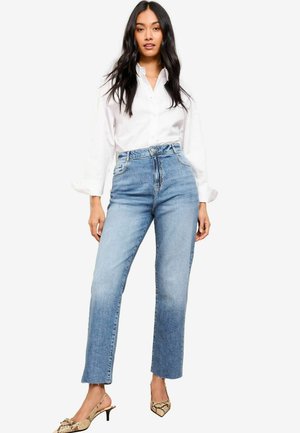 Hoge taille blauwe denim jeans met een rechte snit, onafgewerkte zoom, lichte wassing en twee voorkruiszakken. Gecombineerd met een wit overhemd met knopen.