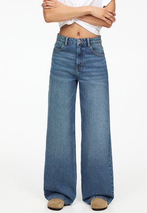 Brede blauwe denim jeans met een hoge taille. Kenmerken zijn een knoopsluiting, een vijfzakkenontwerp en subtiele vervaging op de stof.