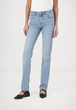 Lichtblauwe denim jeans met een rechte pijp, vijf zakken en een klassieke tailleband. Gecombineerd met zwarte ballerina's met decoratieve eyelets.